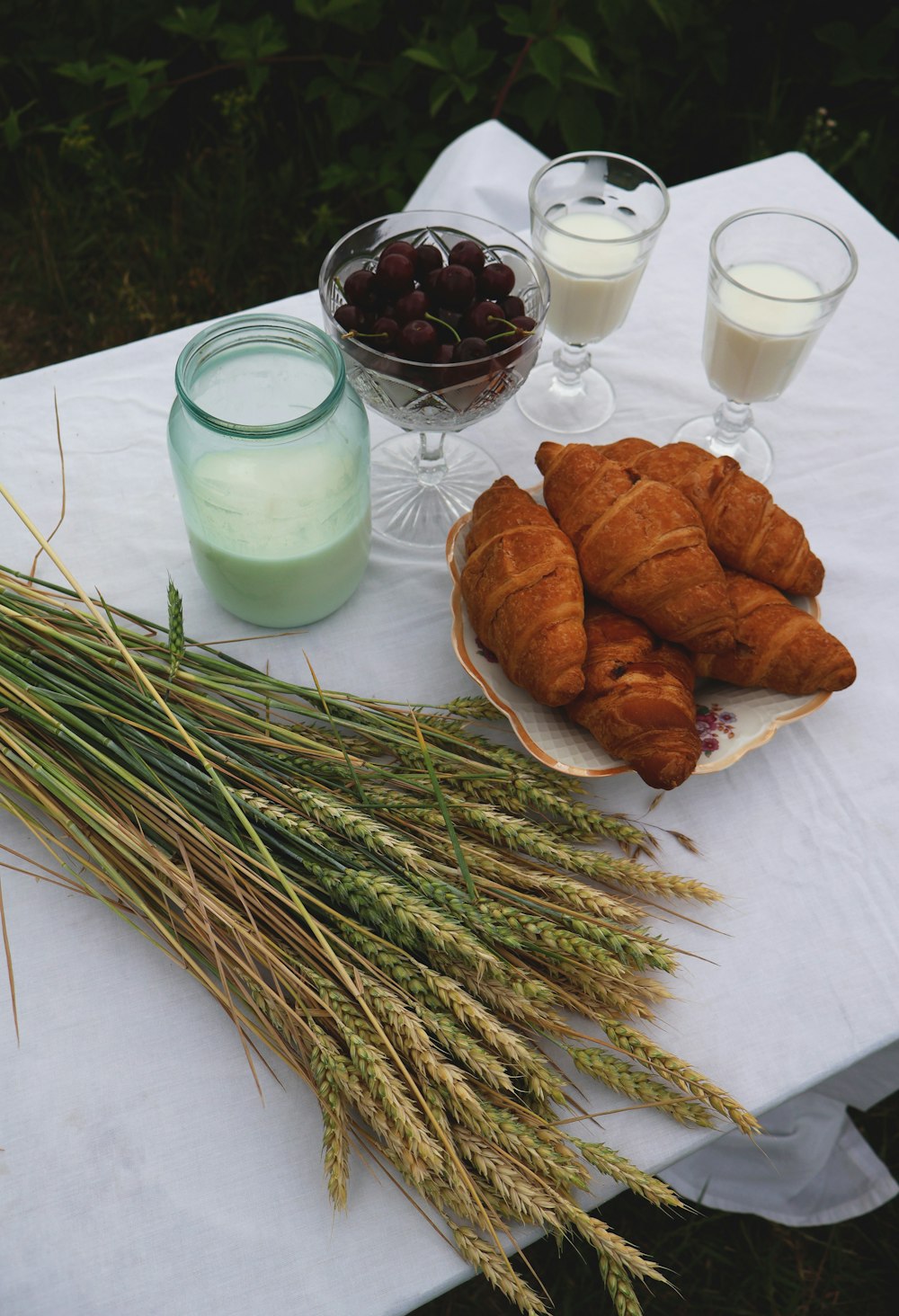 a table topped with croissants and a bowl of cherries