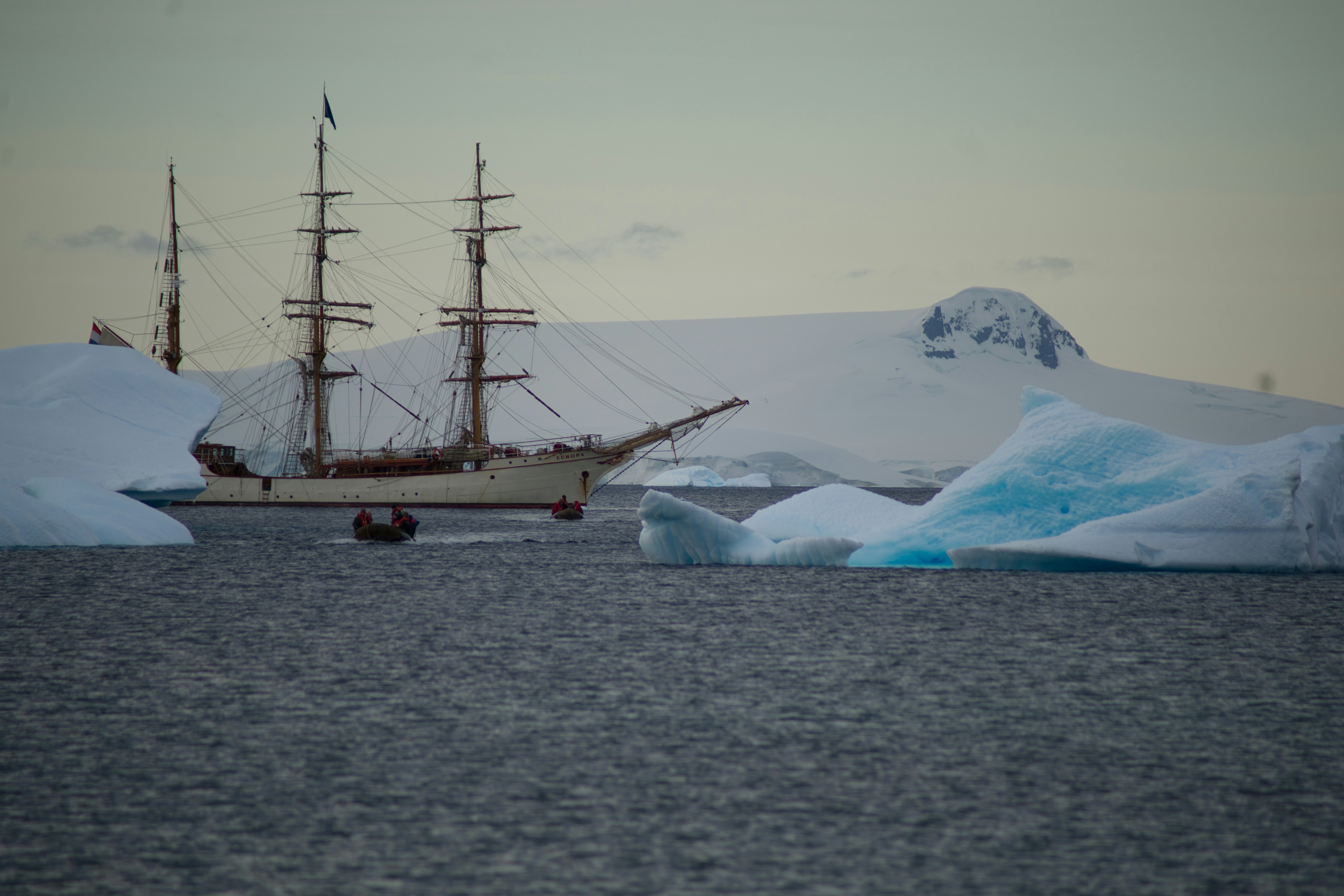 a ship sailing in the ocean near icebergs, 