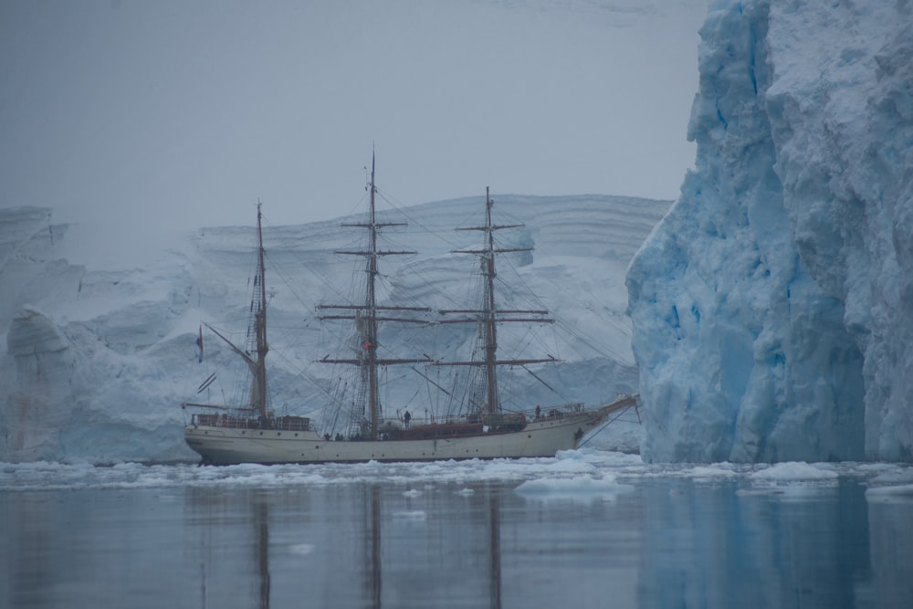 a large boat in a body of water near icebergs