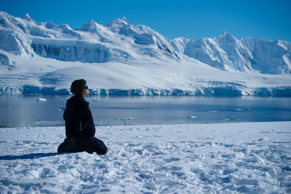 a person sitting in the snow with a mountain in the background