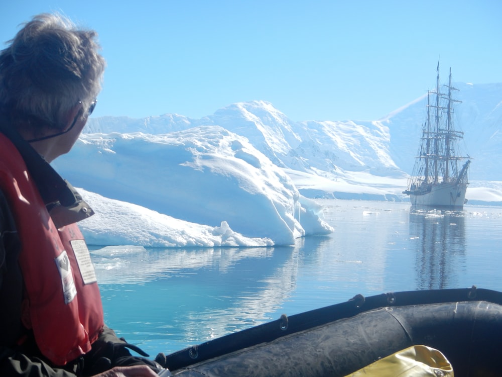 a man in a life jacket looking at a boat in the water