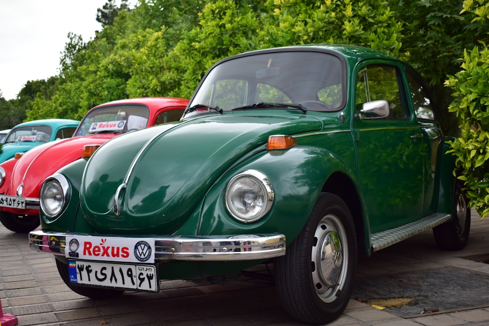 a green vw bug parked next to a red vw bug