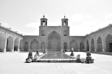 A sunlit courtyard of Jagat Niwas Palace Hotel with intricate stonework and lush greenery.
