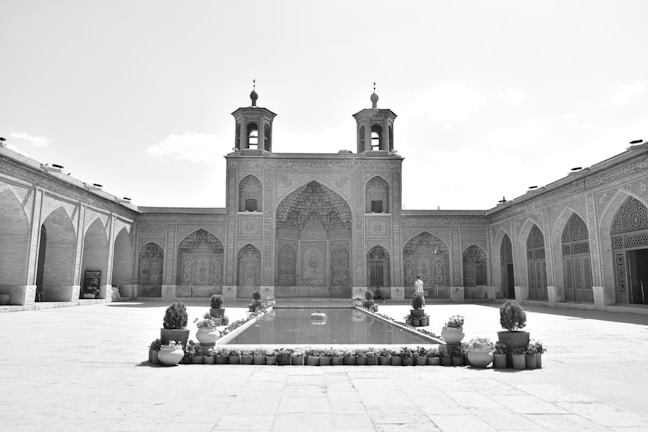 A sunlit courtyard of Jagat Niwas Palace Hotel with intricate stonework and lush greenery.