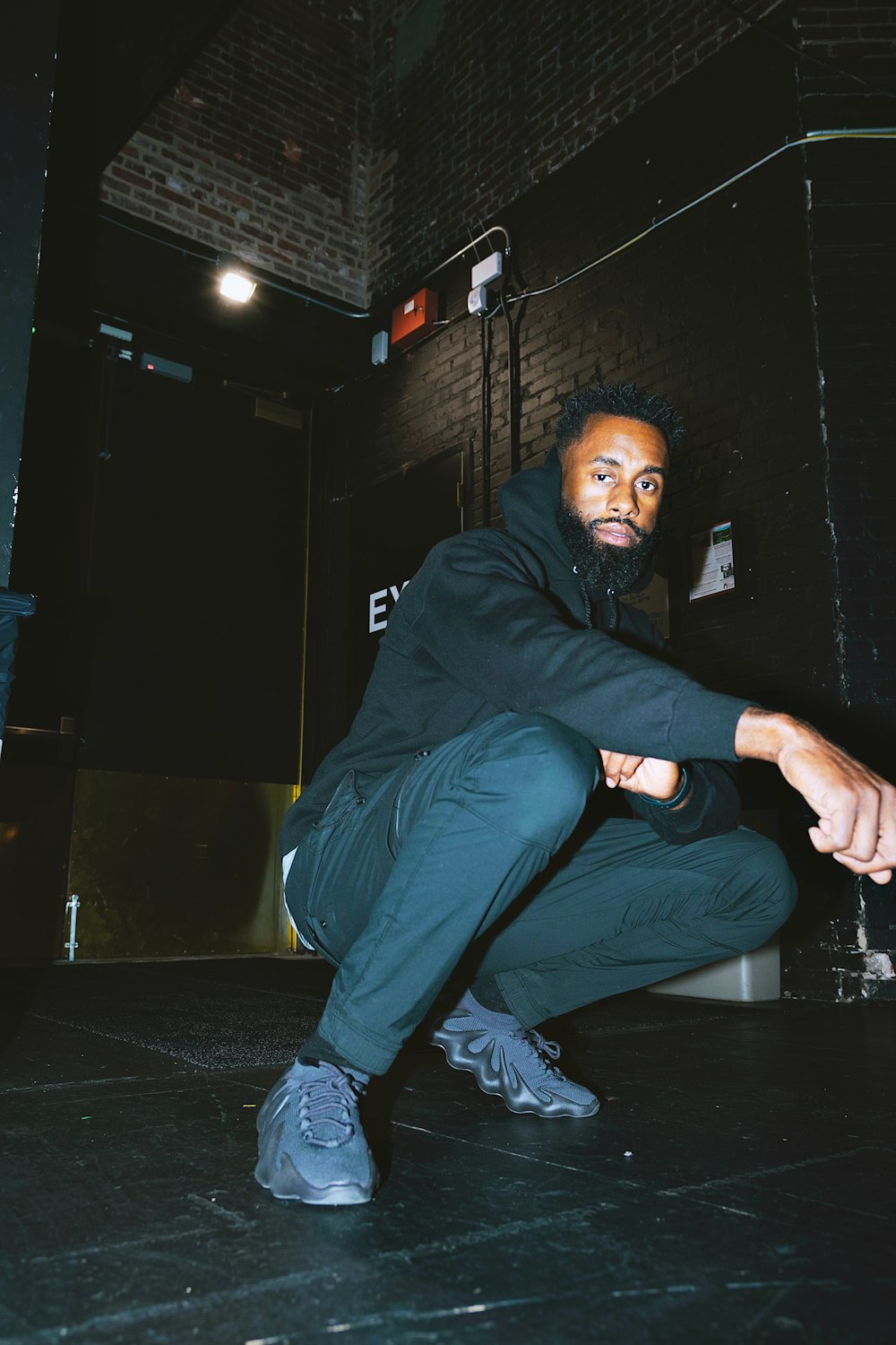 a man squatting on the floor in a dark room