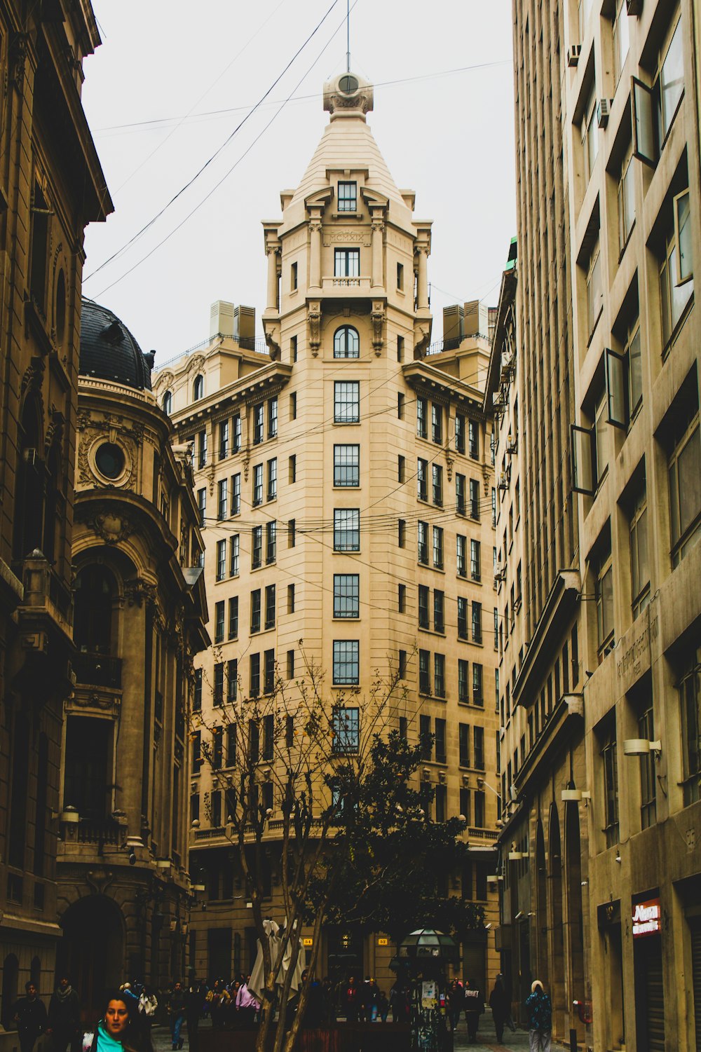 a group of people walking down a street next to tall buildings