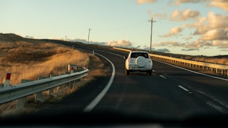 a white truck driving down a road next to a hill