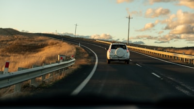a white truck driving down a road next to a hill