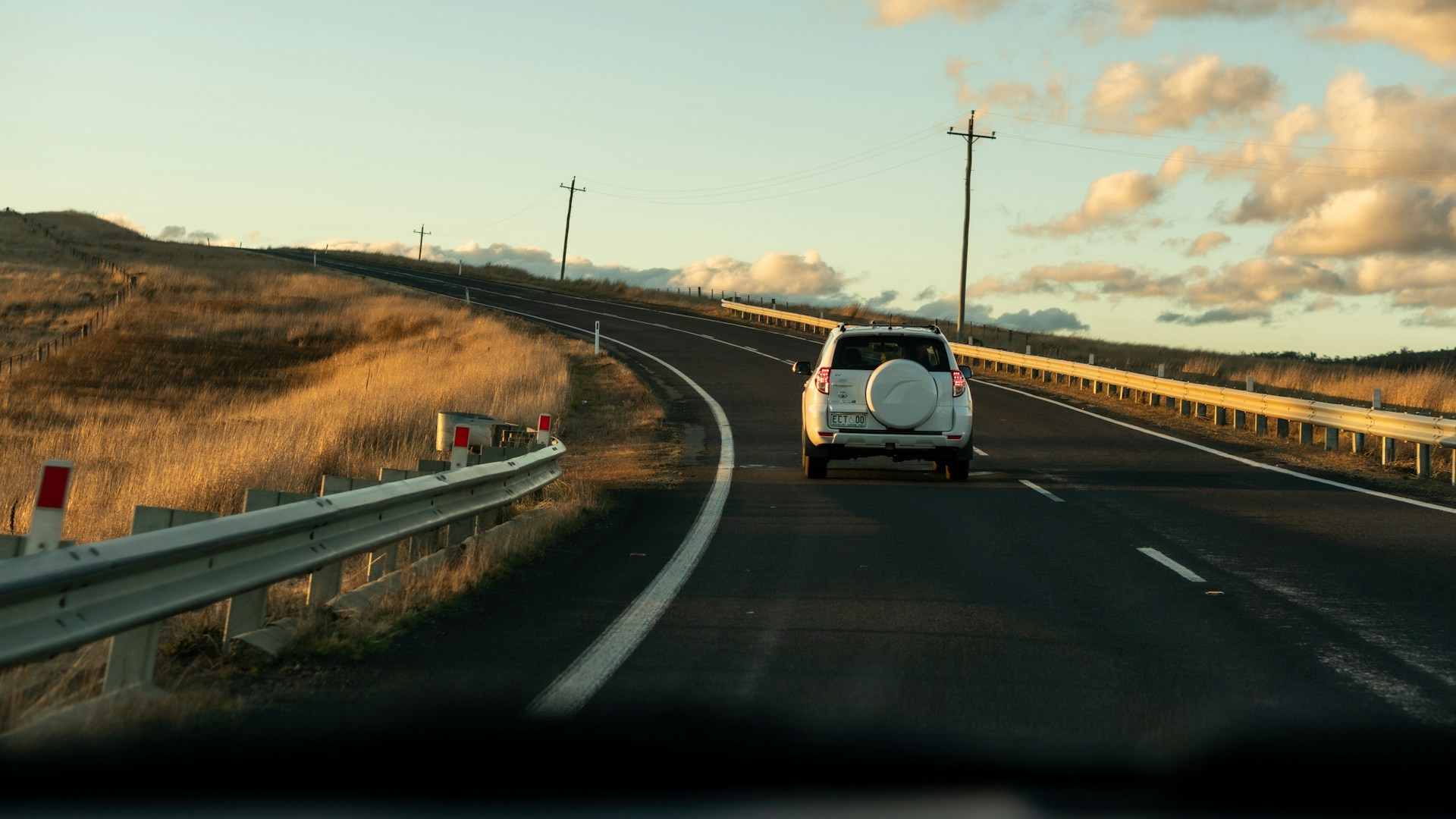 a white truck driving down a road next to a hill