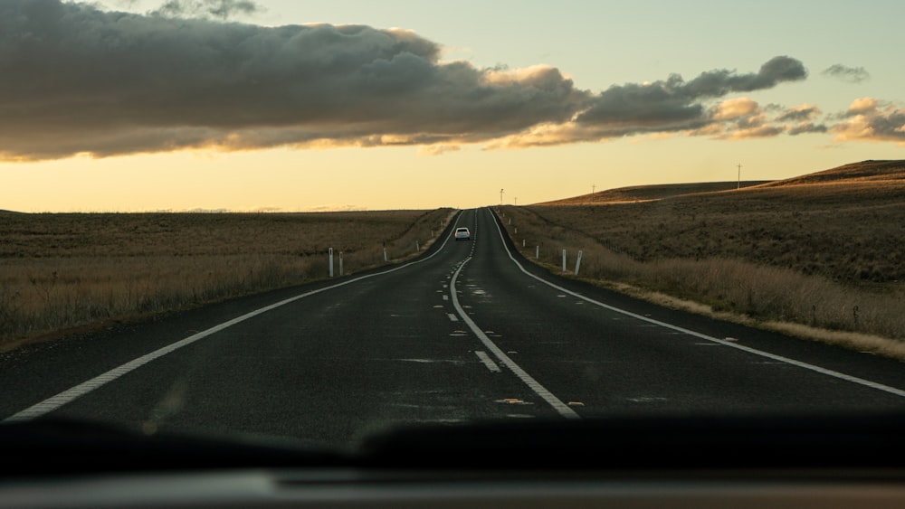 a car driving down a road next to a field