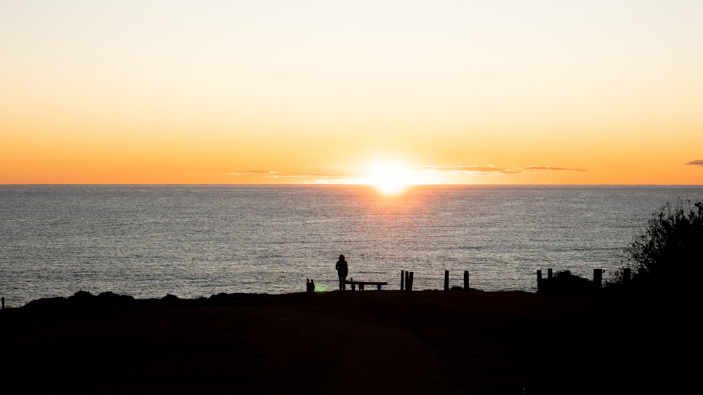 Una persona in piedi su una spiaggia al tramonto