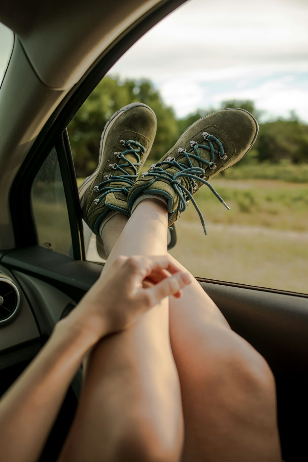 a person sitting in a car with their feet on the steering wheel