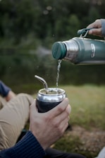 a person is pouring something into a cup