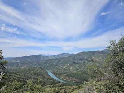A panoramic view of a diverse American landscape featuring mountains, forests, and a winding river.
