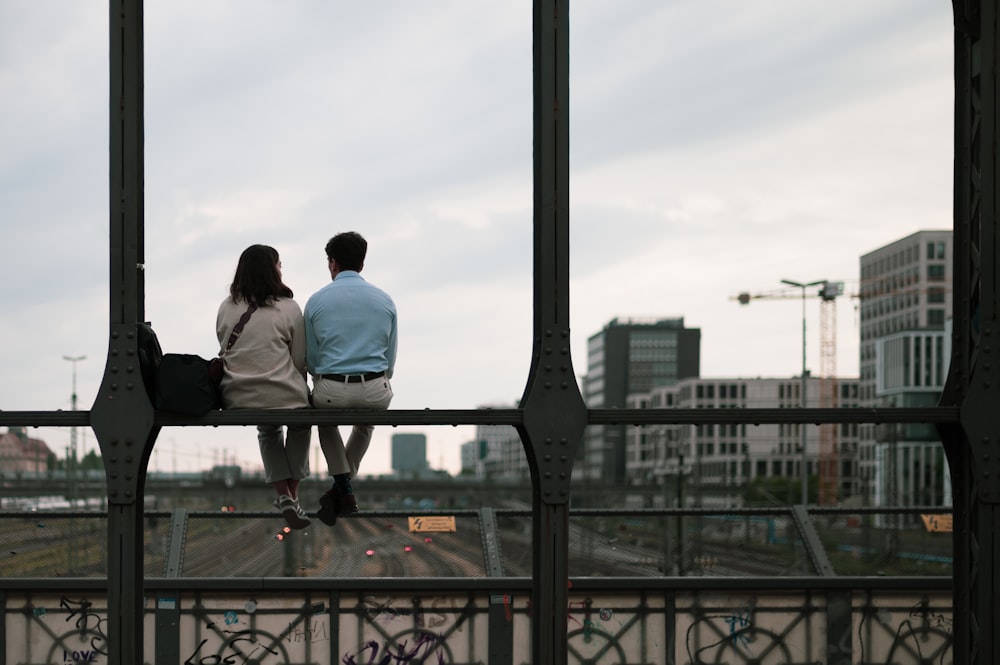 a man and a woman sitting on a rail