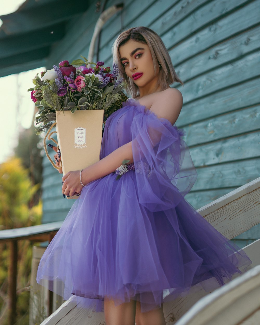 a woman in a purple dress holding a bouquet of flowers