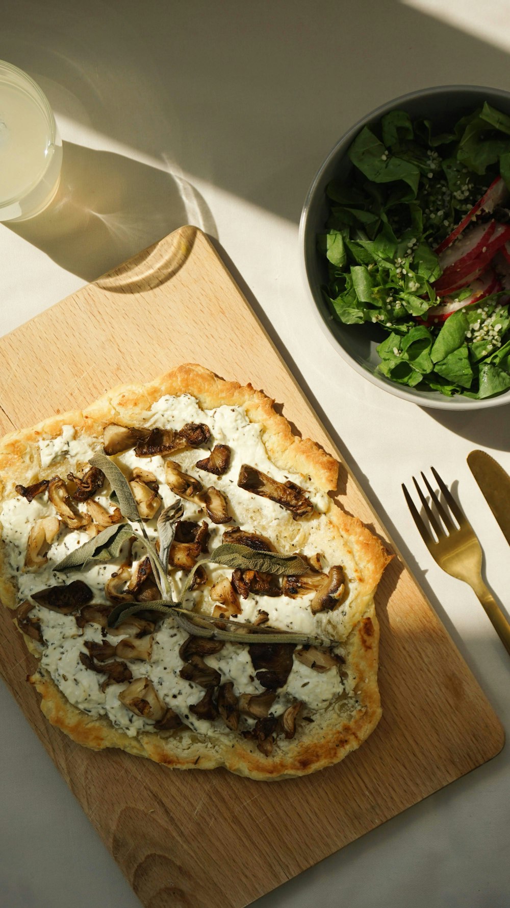 a pizza sitting on top of a cutting board next to a salad