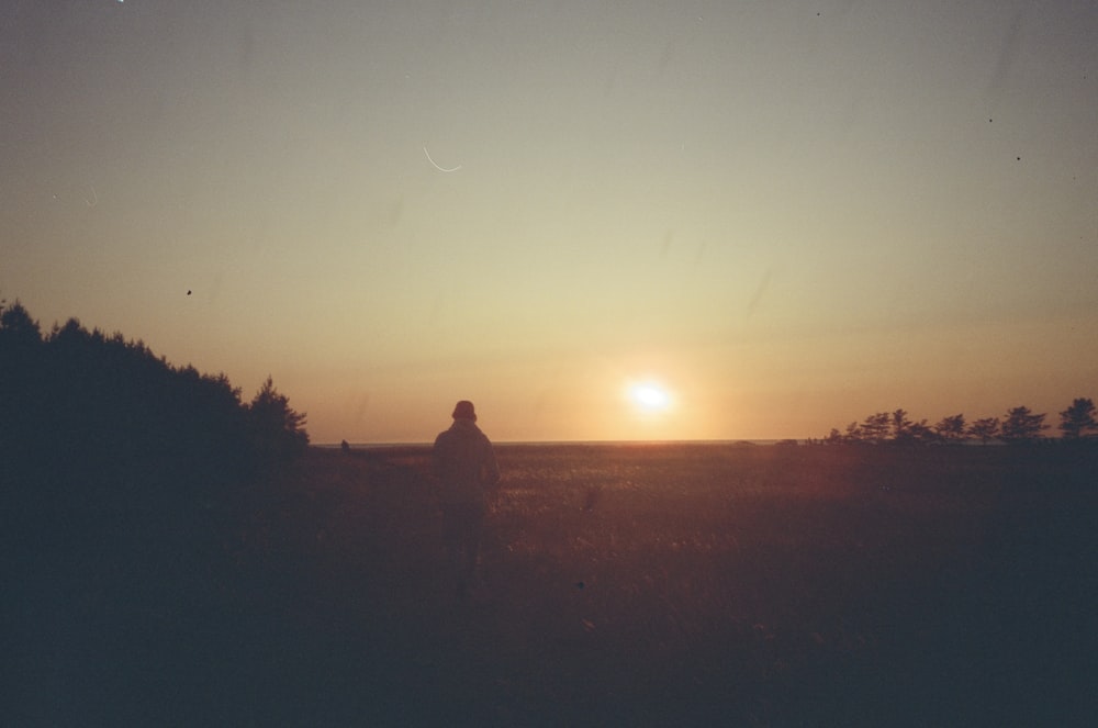 a person standing in a field at sunset