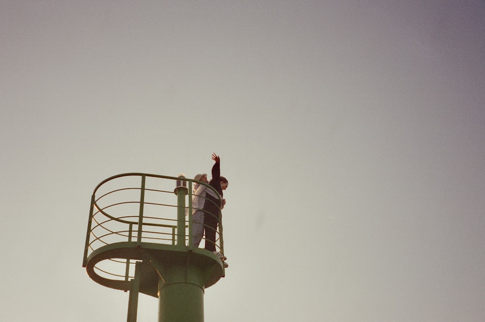 a man standing on top of a green tower