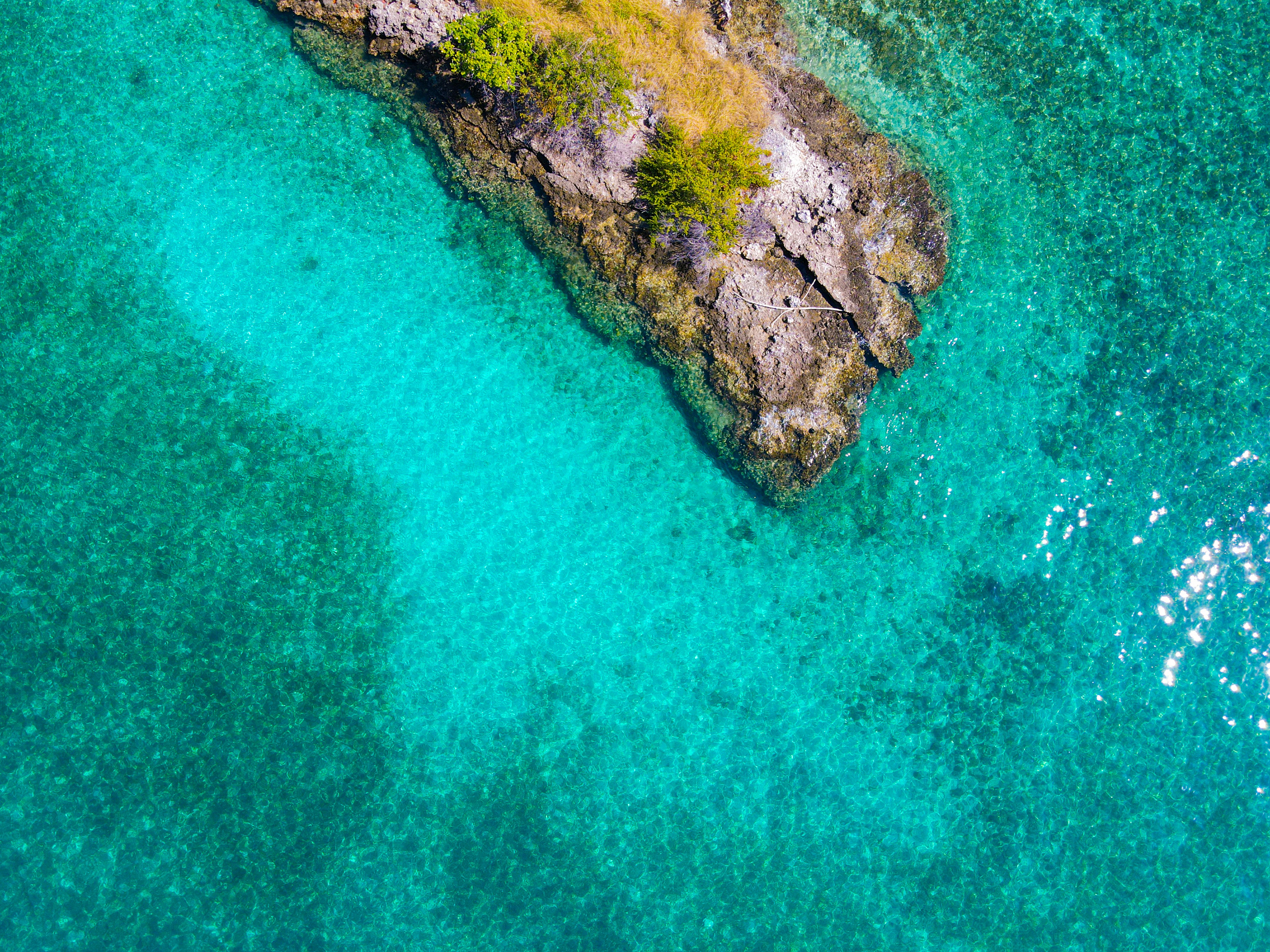 an aerial view of a rock outcropping in the ocean, 