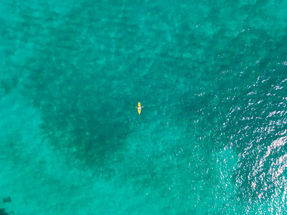 an aerial view of a yellow surfboard in the ocean
