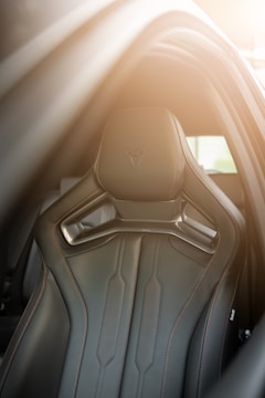 A sleek car seat with detailed stitching and a modern design. The lighting suggests a sunny atmosphere, highlighting the contours of the seat.
