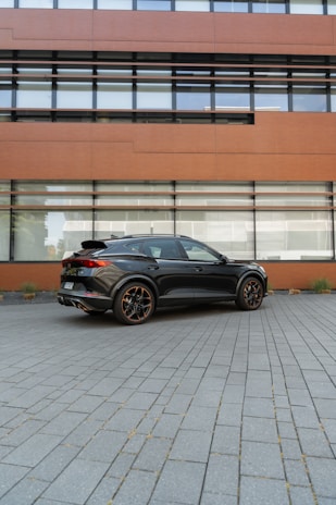 A sleek black luxury executive car parked in front of a modern São Paulo office building.