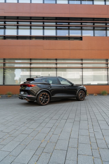A sleek black Corolla parked in front of a modern office building, showcasing executive transport.