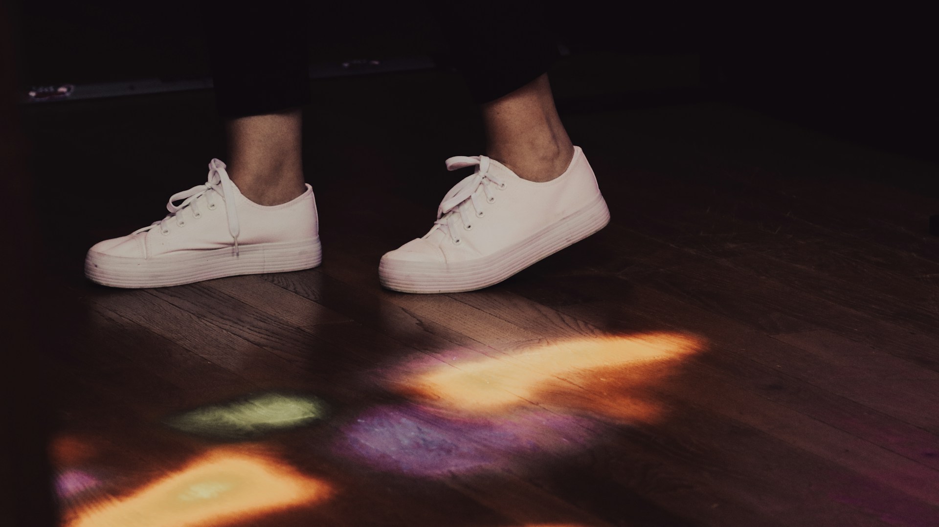 a person standing on a wooden floor with white shoes