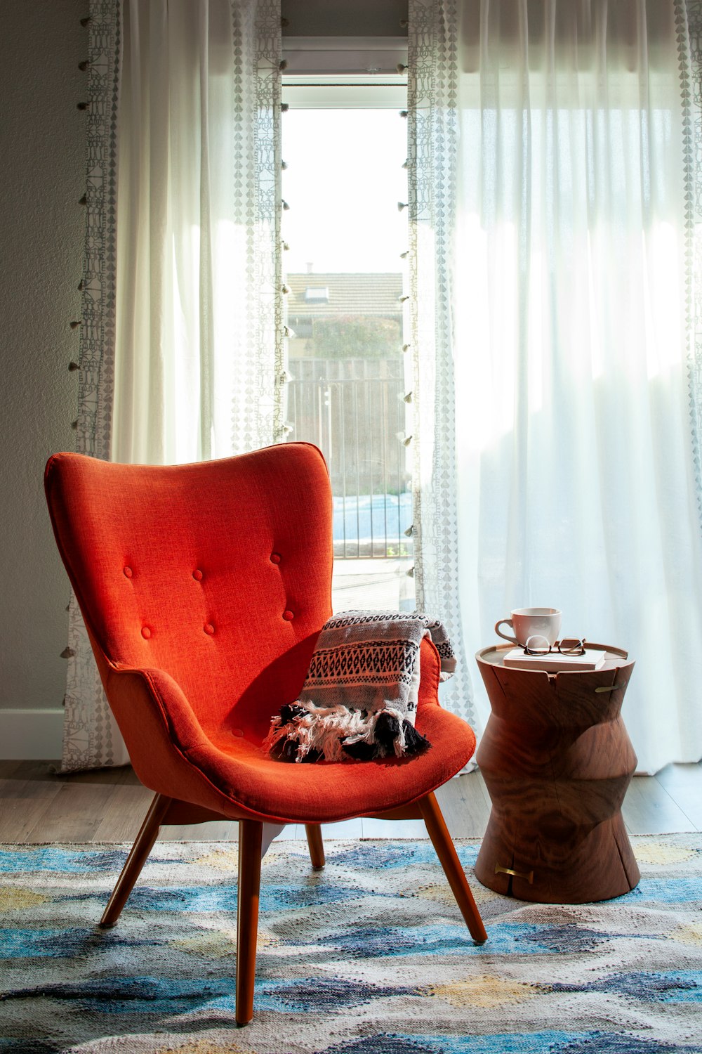 a red chair sitting in a living room next to a window