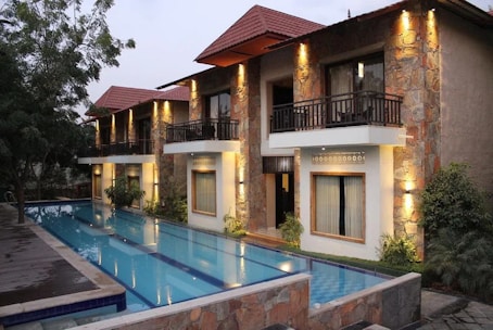 Modern family house with concrete pool under bright sunlight in a warm climate.