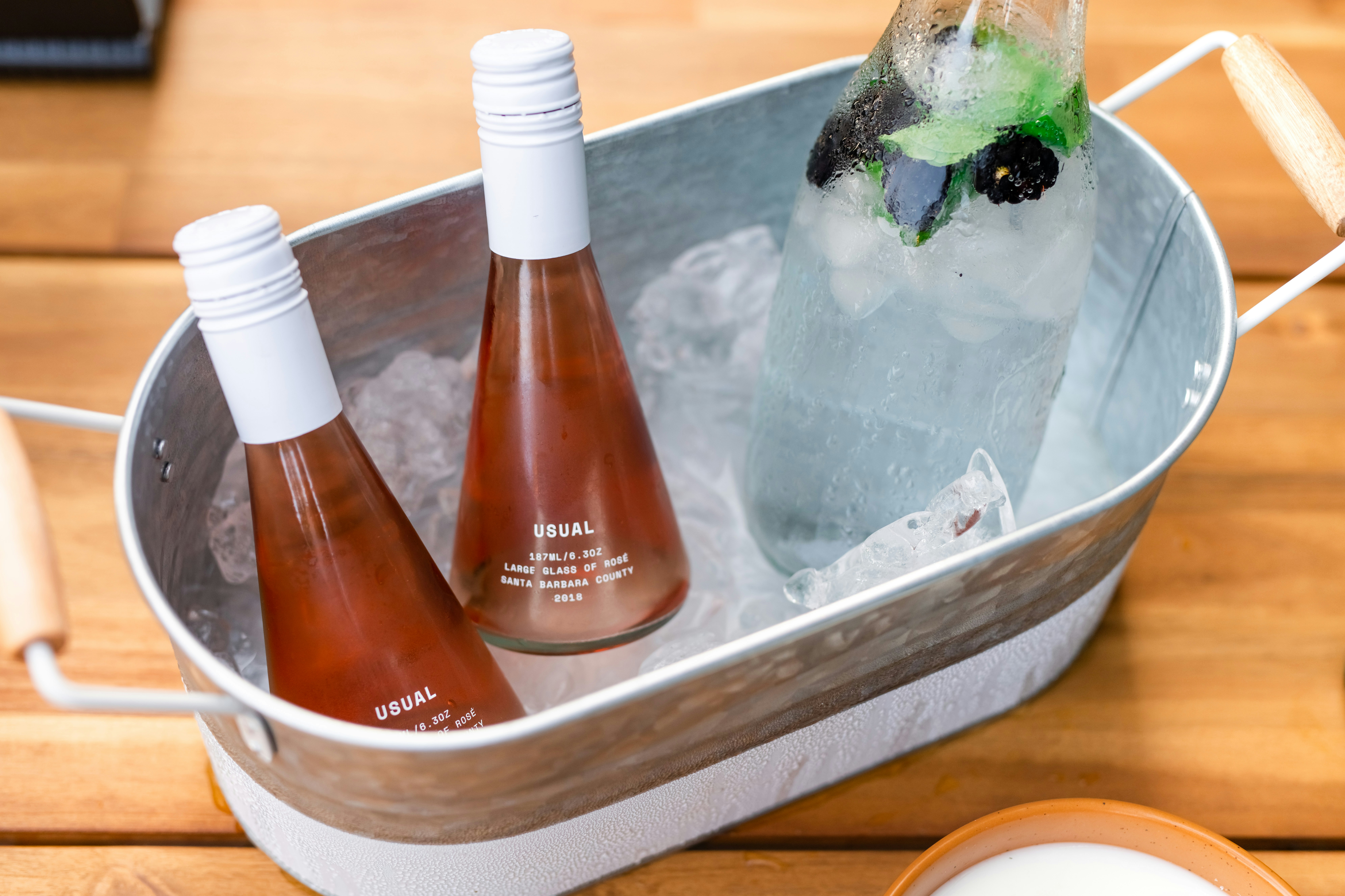 An inviting ice bucket filled with chilled beer bottles and refreshing mojito, perfect for summer gatherings!