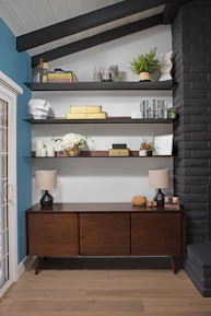 A slim depth media storage credenza alongside a curved high back fabric loveseat in a bright, airy space.