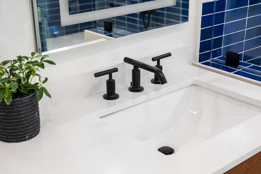 a bathroom sink with a black faucet and a blue tiled wall