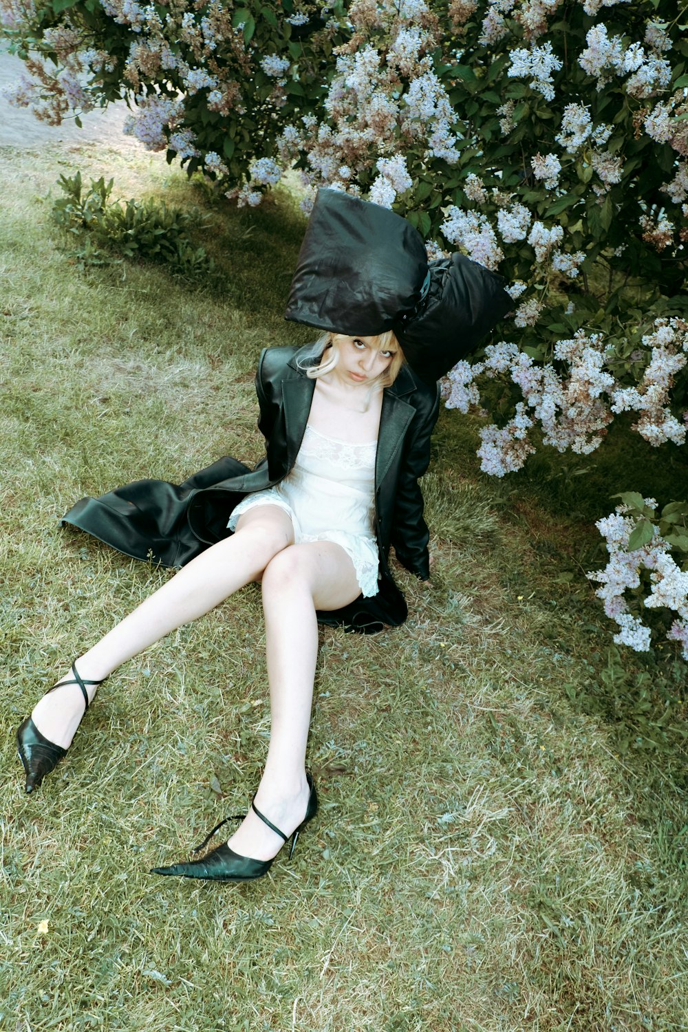 a woman sitting in the grass with a hat on her head