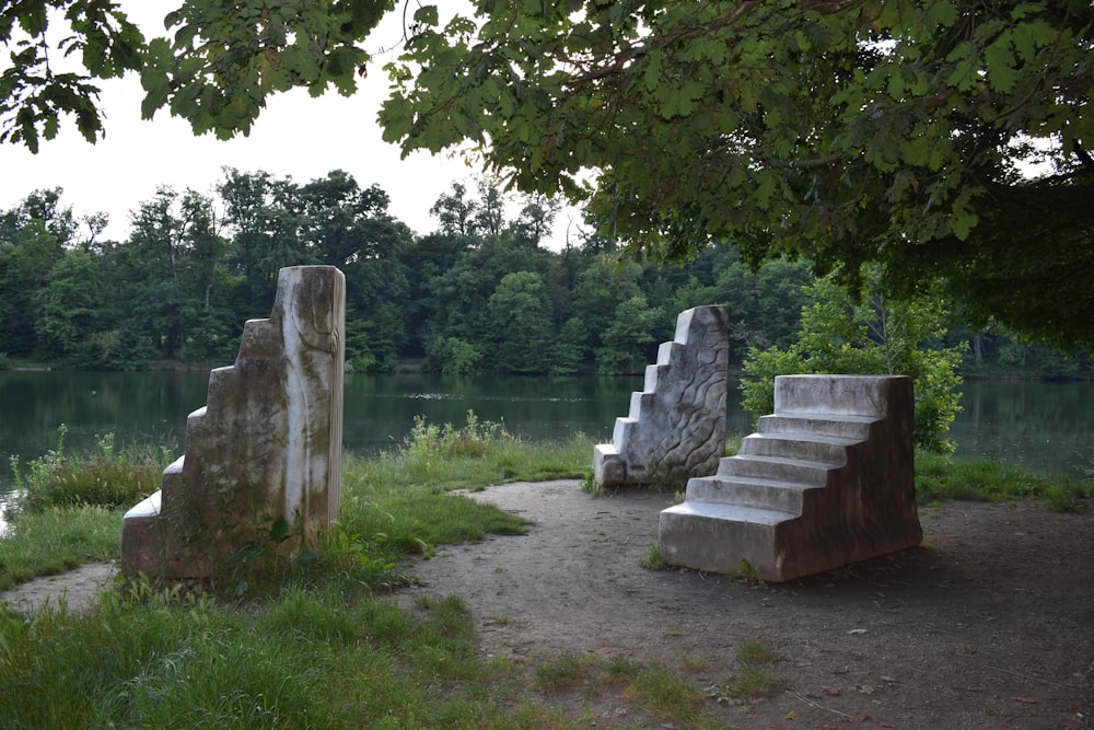 a couple of stone benches sitting next to a lake