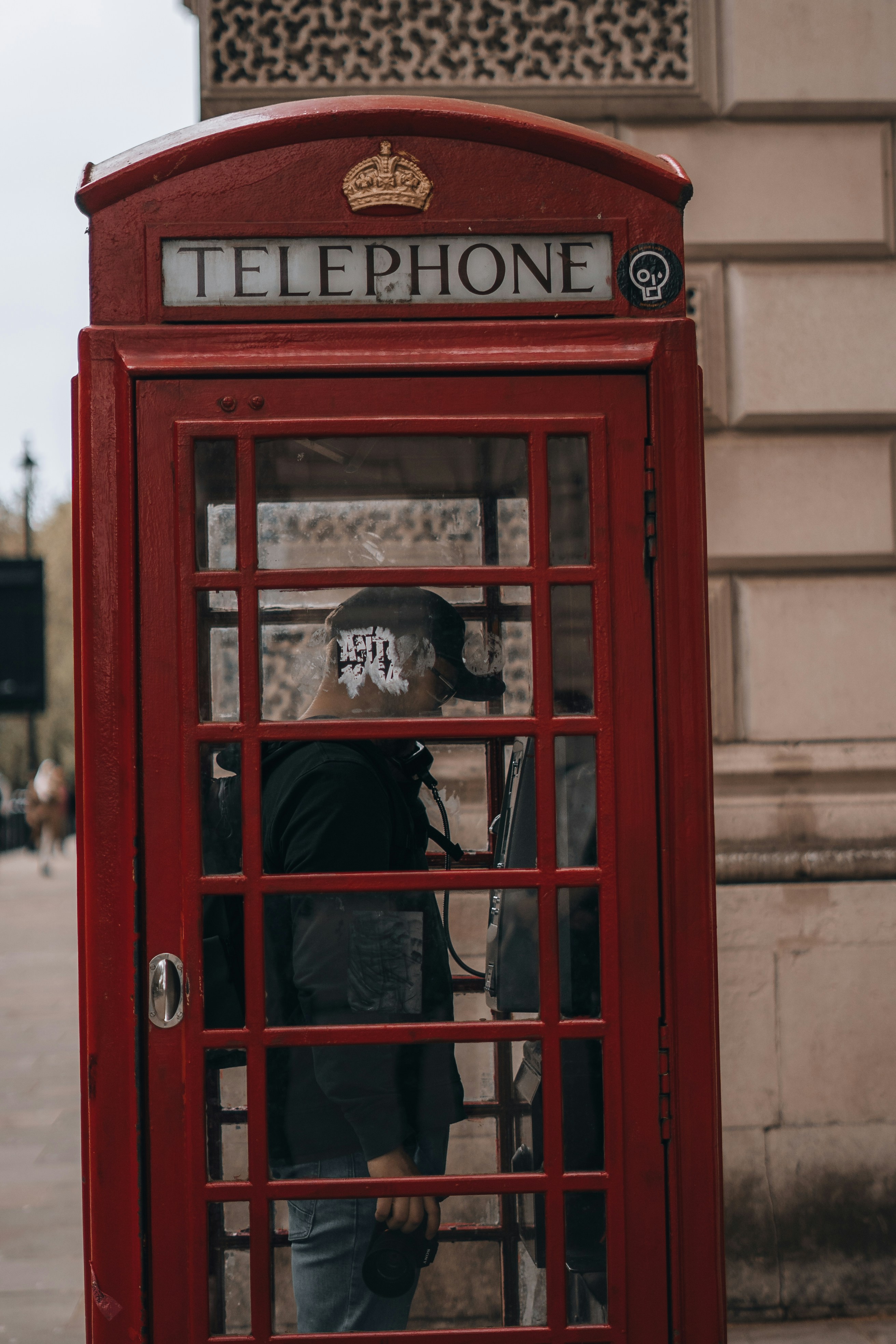 a man standing in a red telephone booth