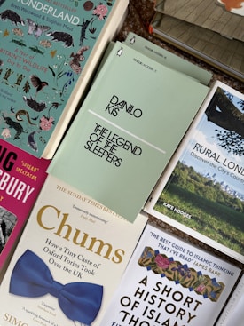 A collection of books arranged in a somewhat overlapping pattern, including titles with varied themes and cover designs such as wildlife, historical analysis, and cultural exploration. Notable titles include 'The Legend of the Sleepers' by Danilo Kis, and 'Chums', which features a distinctive blue bow tie image on its cover.