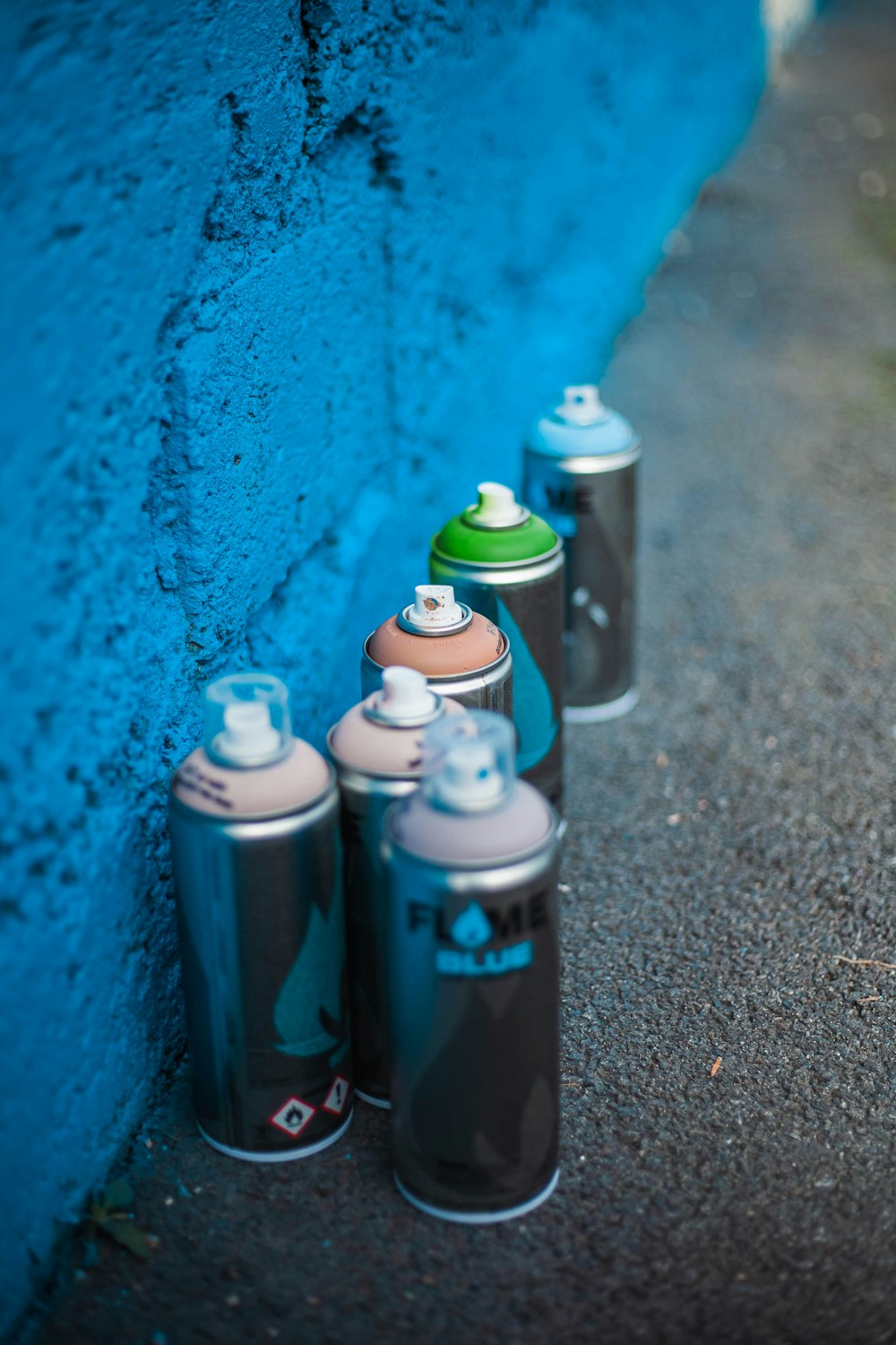 a group of spray cans sitting next to a blue wall