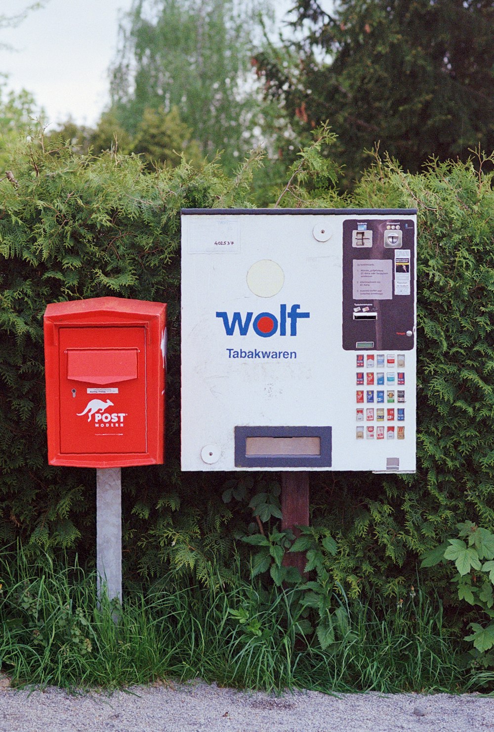 Una cassetta postale rossa seduta accanto a una scatola bianca