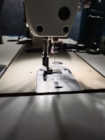 Technician adjusting the tension dial on a modern sewing machine.