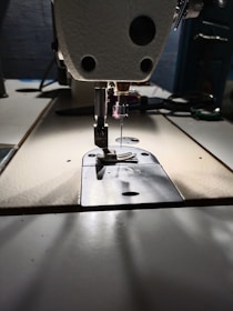 A close-up of a sewing machine with colorful fabrics and threads around it.