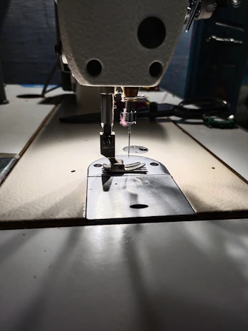Close-up of a Juki single needle sewing machine stitching fine fabric with precision.