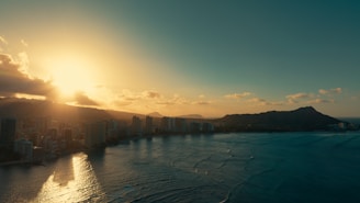 A panoramic view of Honolulu coastline with a sunset casting warm light over the ocean.