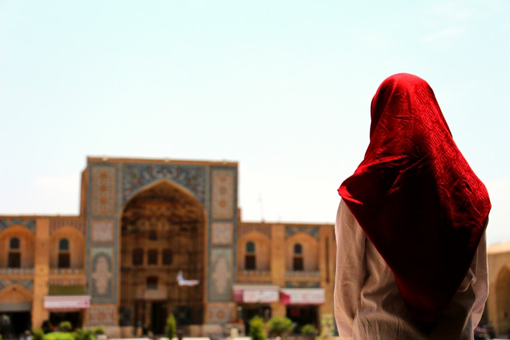 a woman in a red head scarf standing in front of a building
