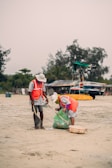 a man and a woman are cleaning the sand