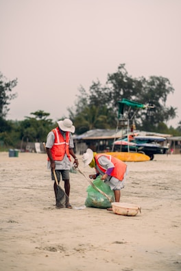a man and a woman are cleaning the sand