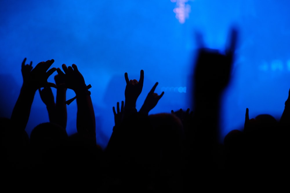 a crowd of people raising their hands in the air