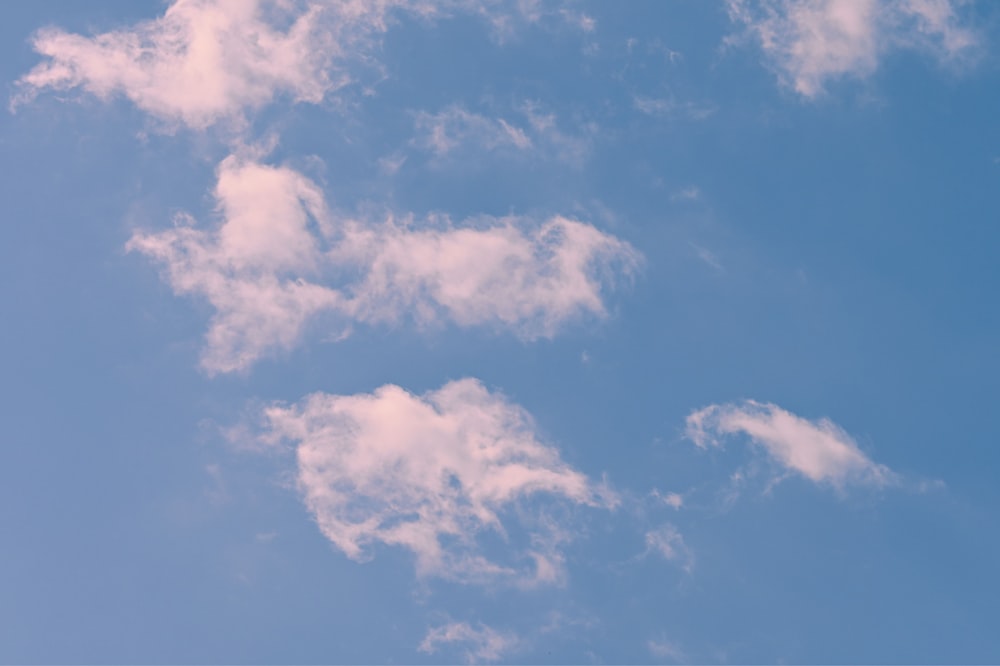 a plane flying through a blue sky with white clouds