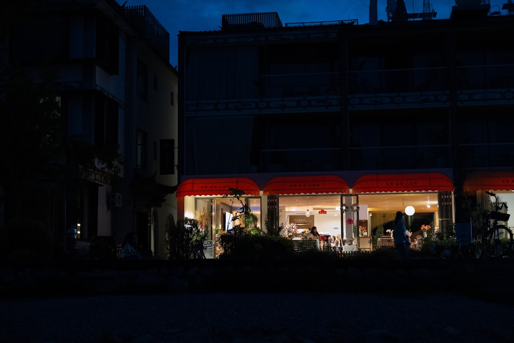 a building lit up at night with people outside